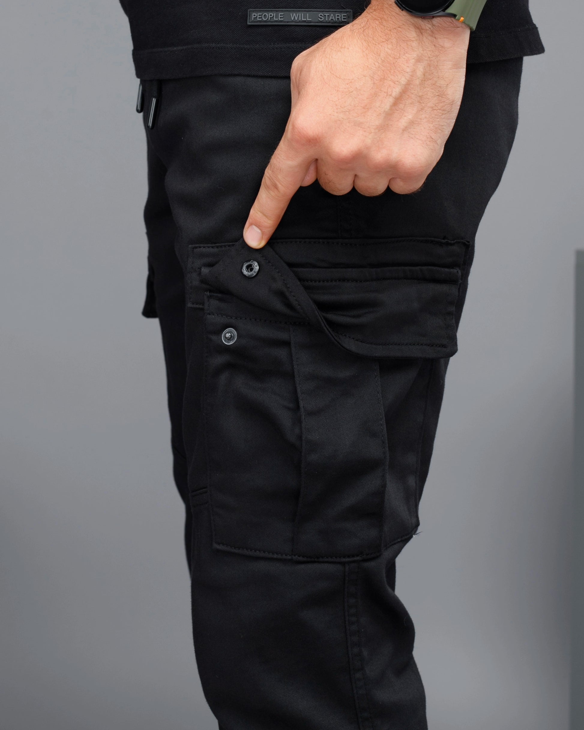Black cargo pants with a focus on the pocket area against a gray background