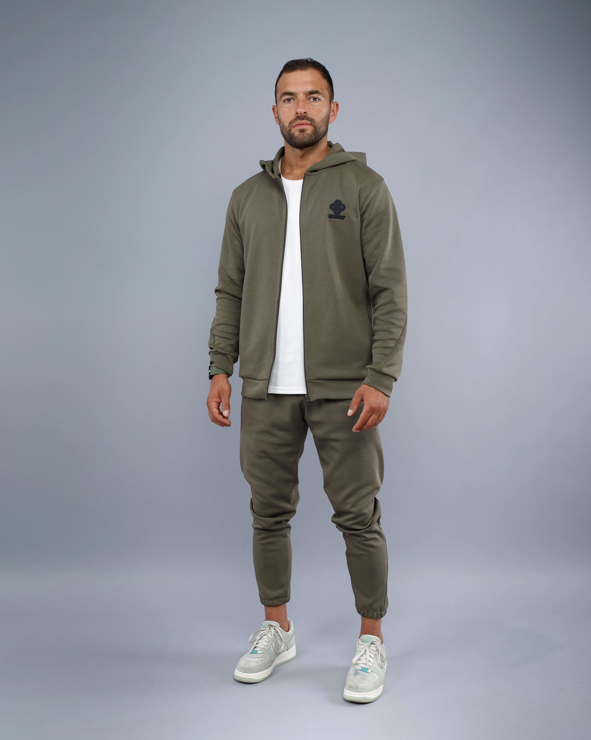 Man wearing a green tracksuit with a logo on a gray background
