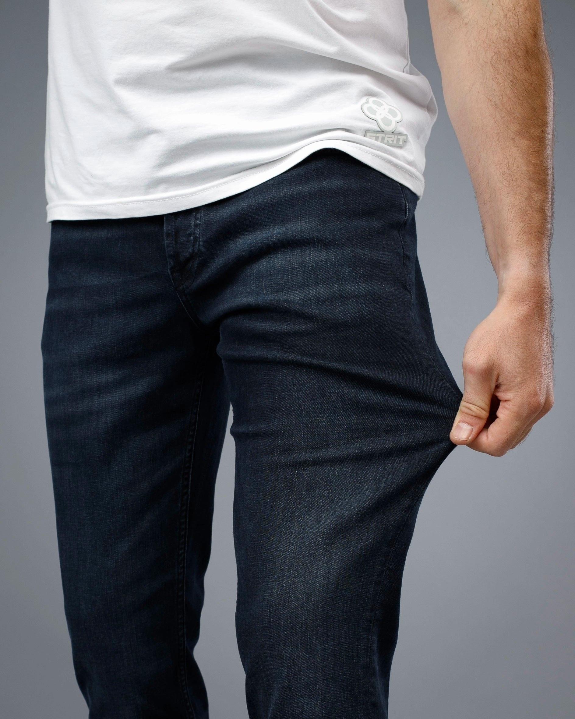 Person wearing dark blue jeans and a white t-shirt on a gray background