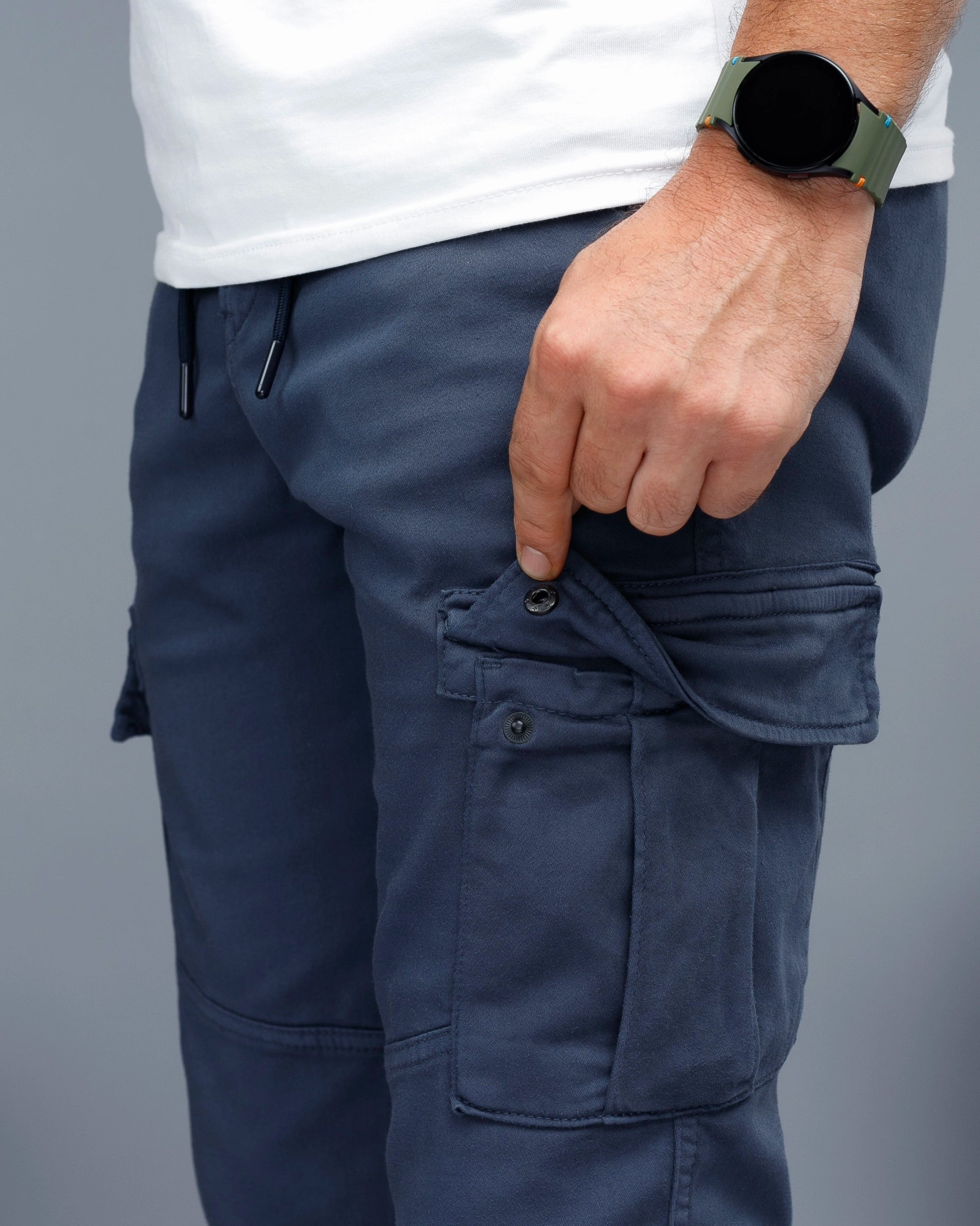 Person wearing navy cargo pants with a gray background
