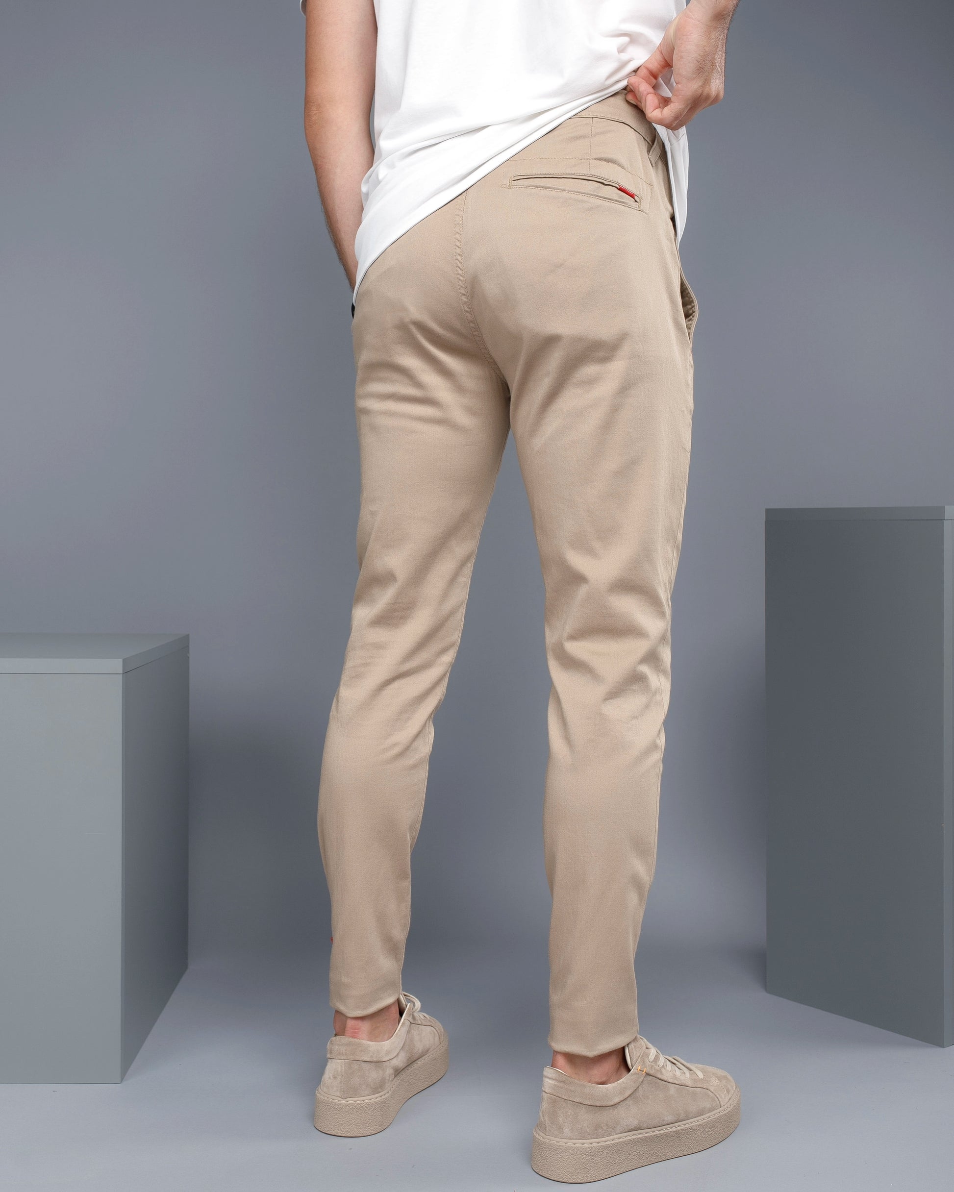 Person wearing beige pants and white shirt against a gray background