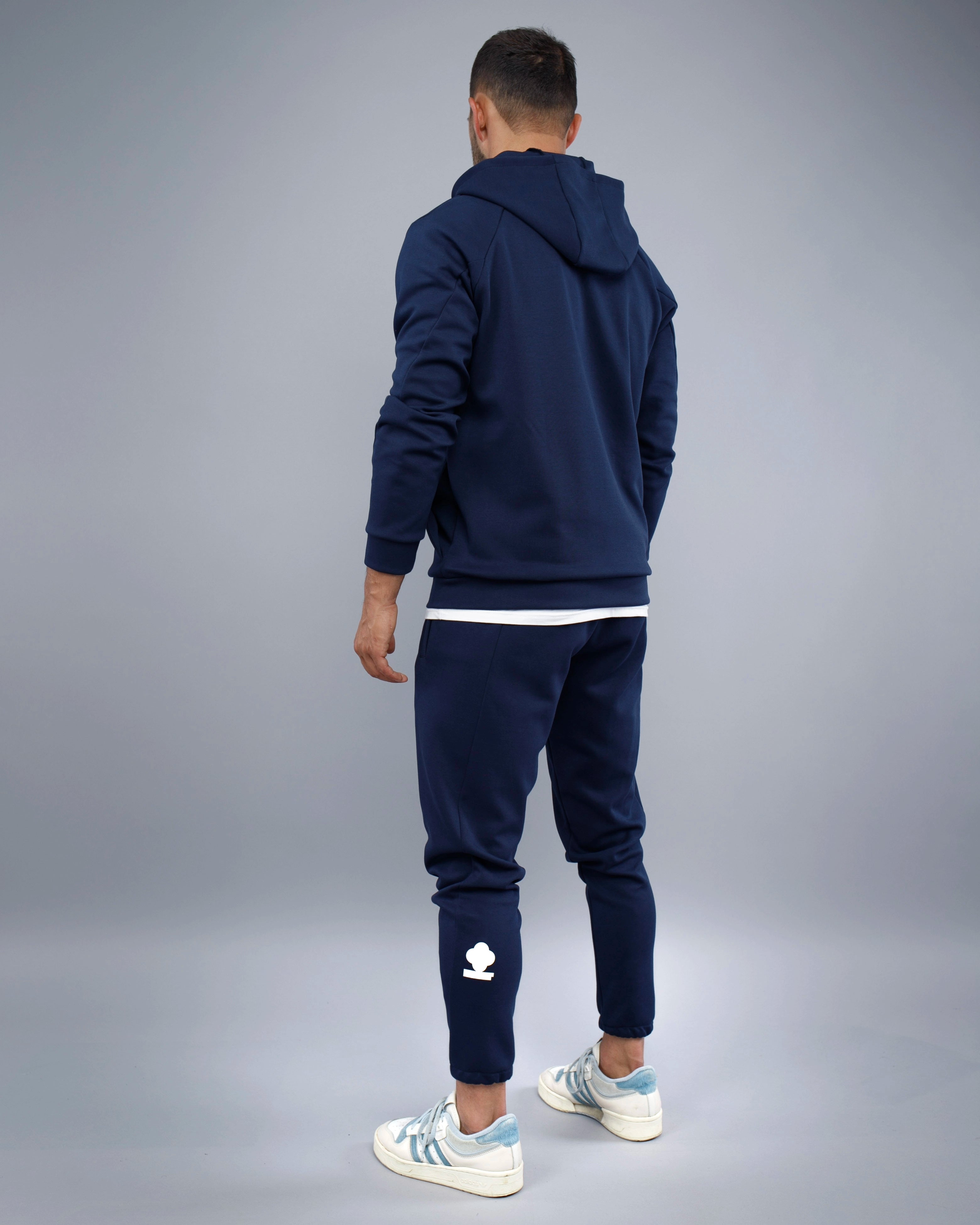 Person wearing a navy tracksuit with a gray background
