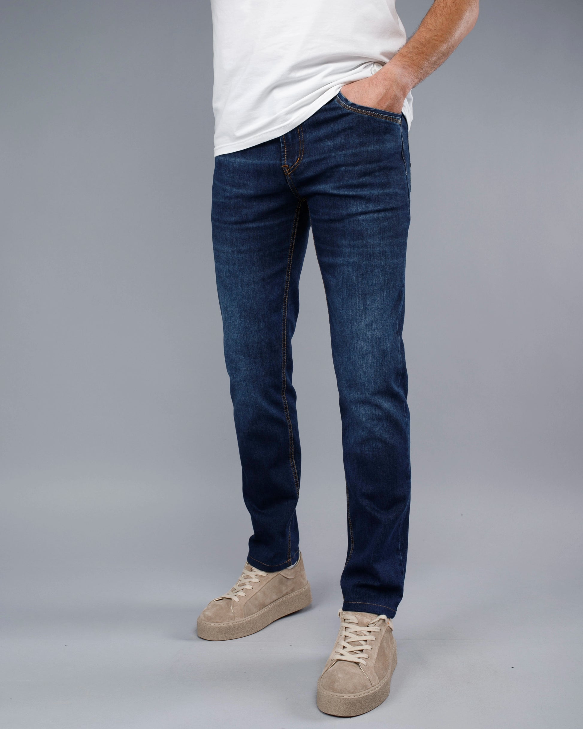 Person wearing blue jeans and a white shirt on a gray background