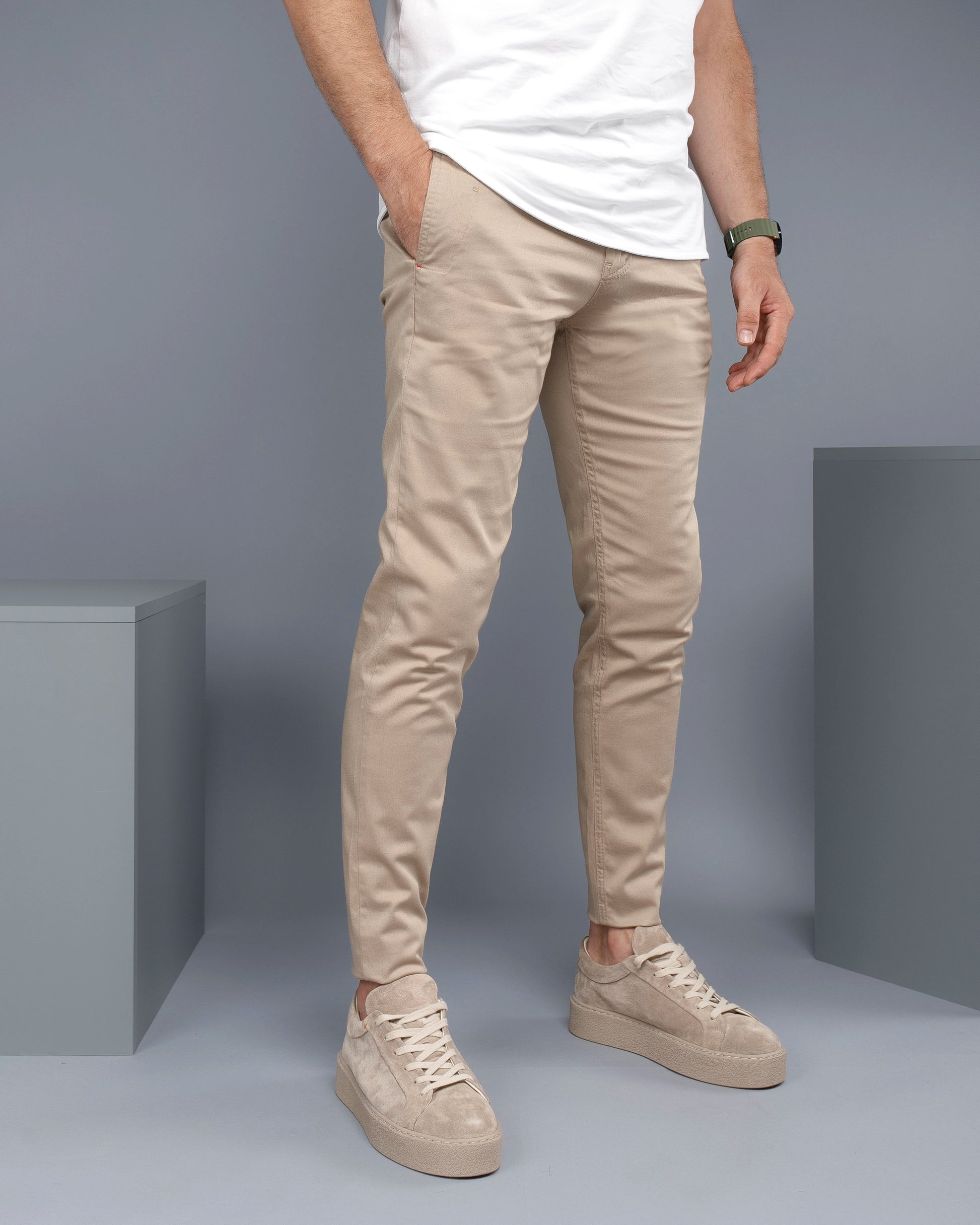 Person wearing beige pants and shoes against a gray background