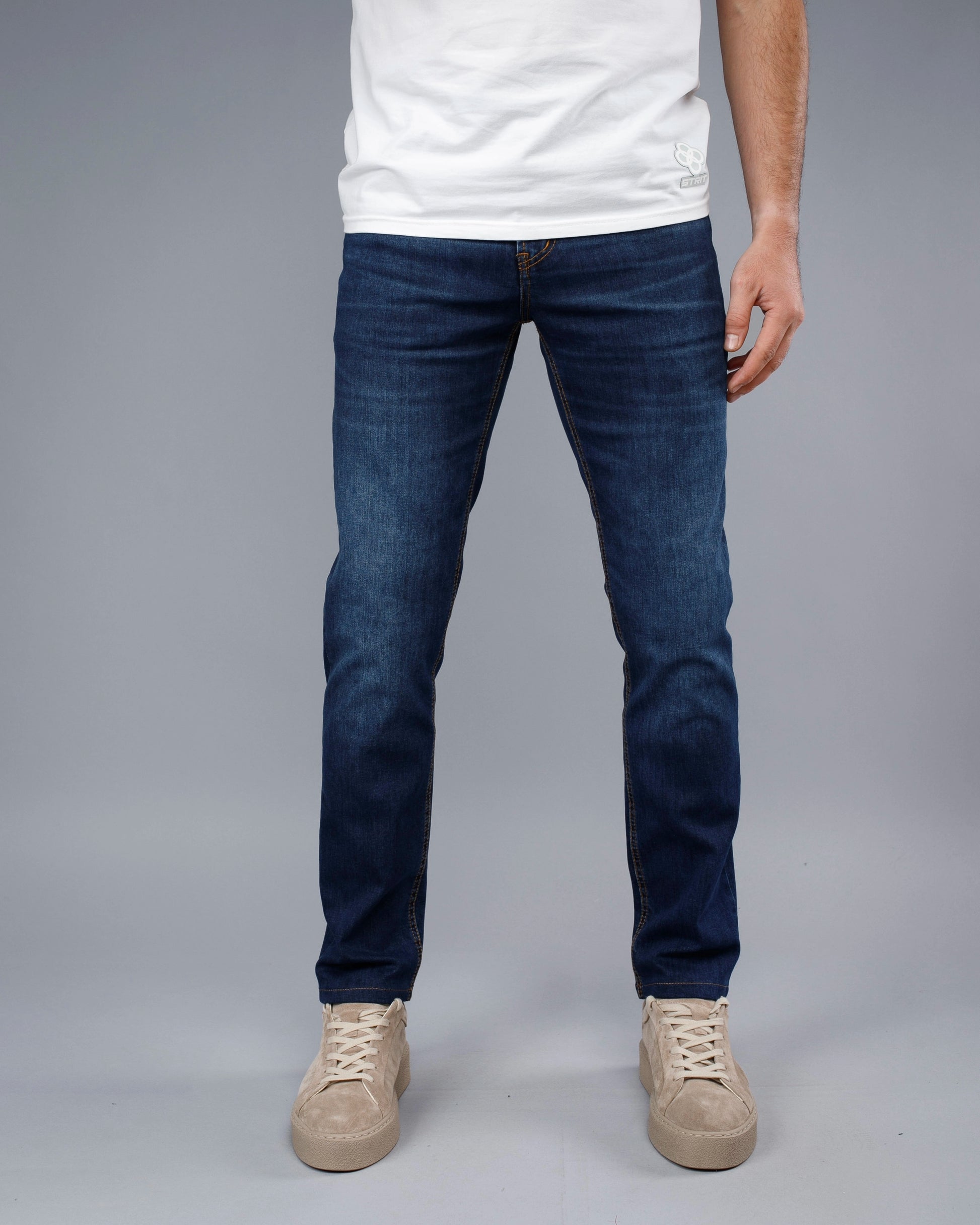 Person wearing blue jeans and a white shirt on a gray background