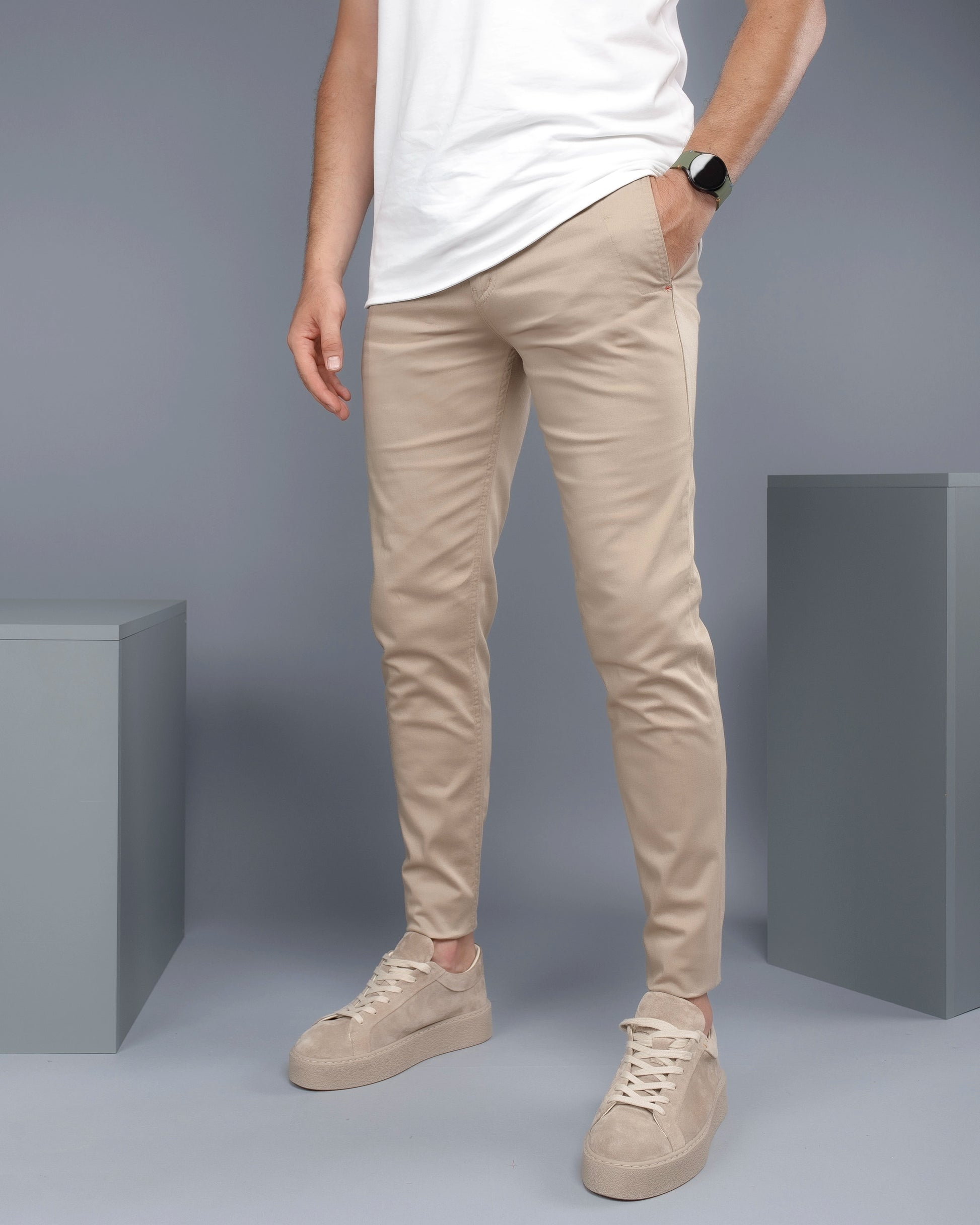 Person wearing beige pants and shoes against a gray background