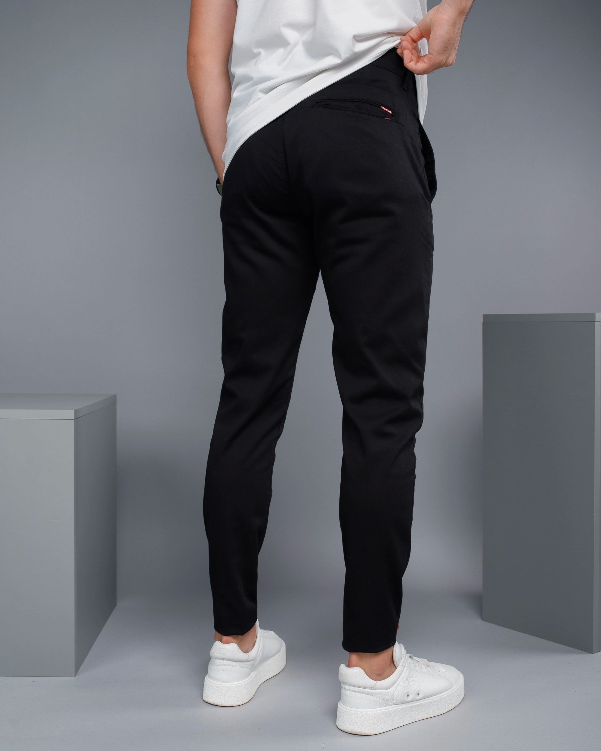 Person wearing black pants and white shoes on a gray background