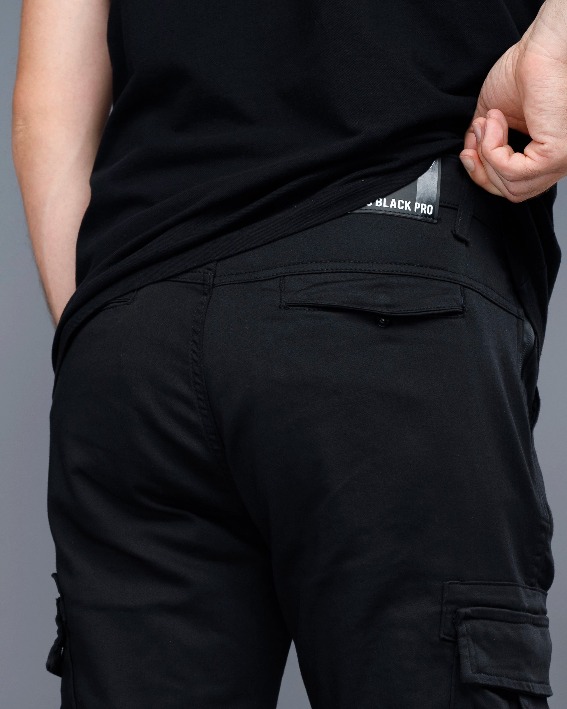 Person wearing black pants with a visible brand label on a gray background