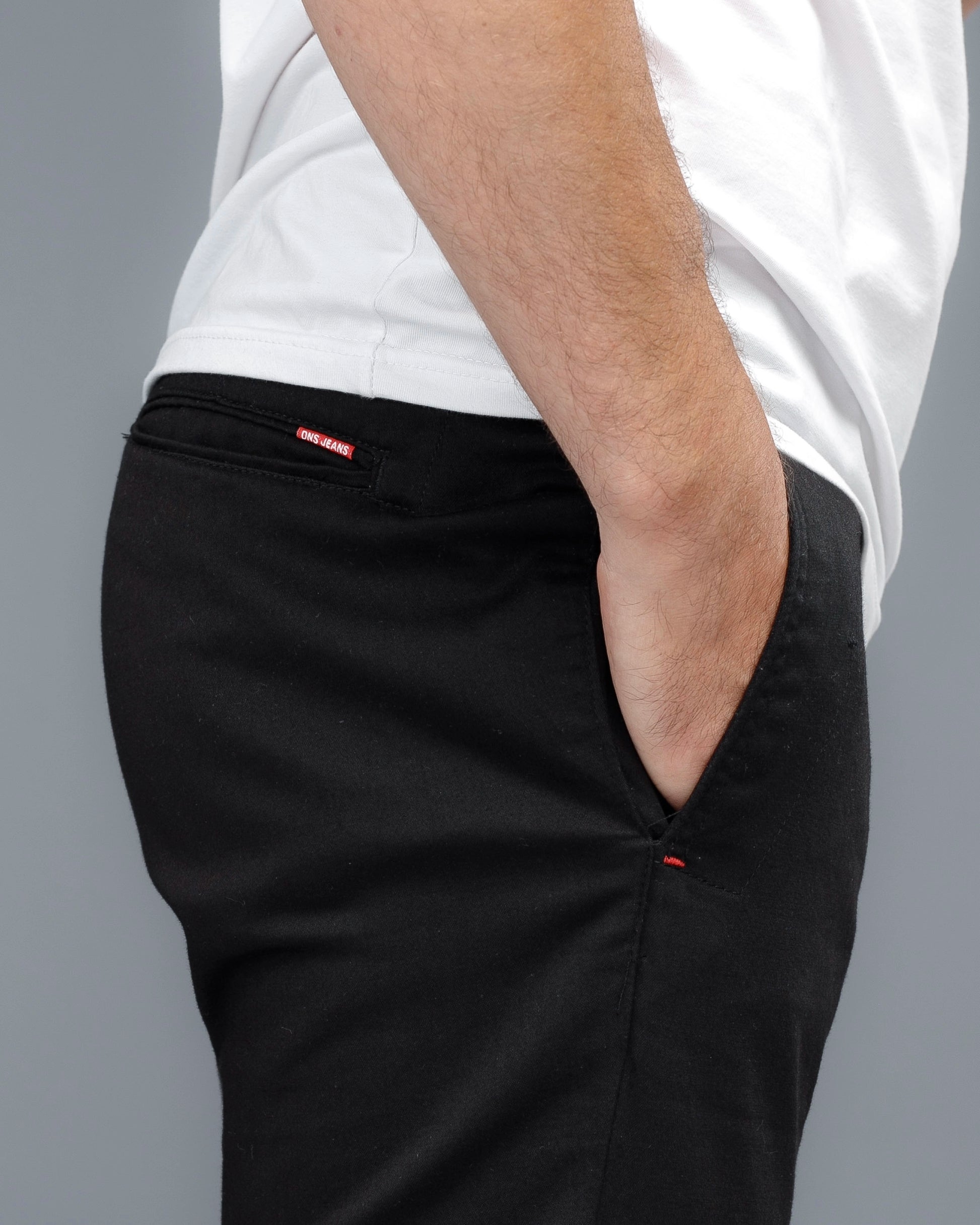 Person wearing black pants with a white shirt on a gray background