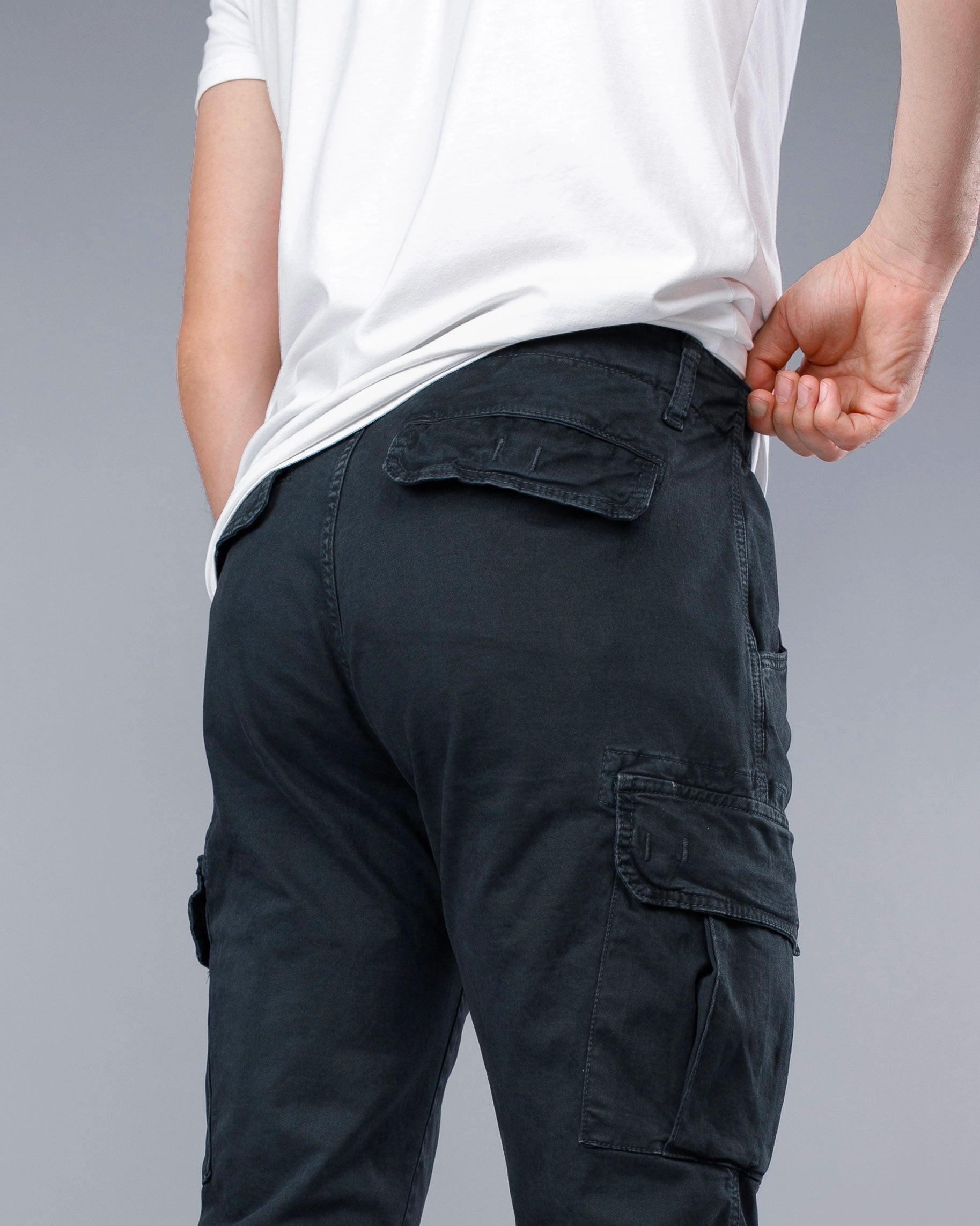 Person wearing black cargo pants on a gray background
