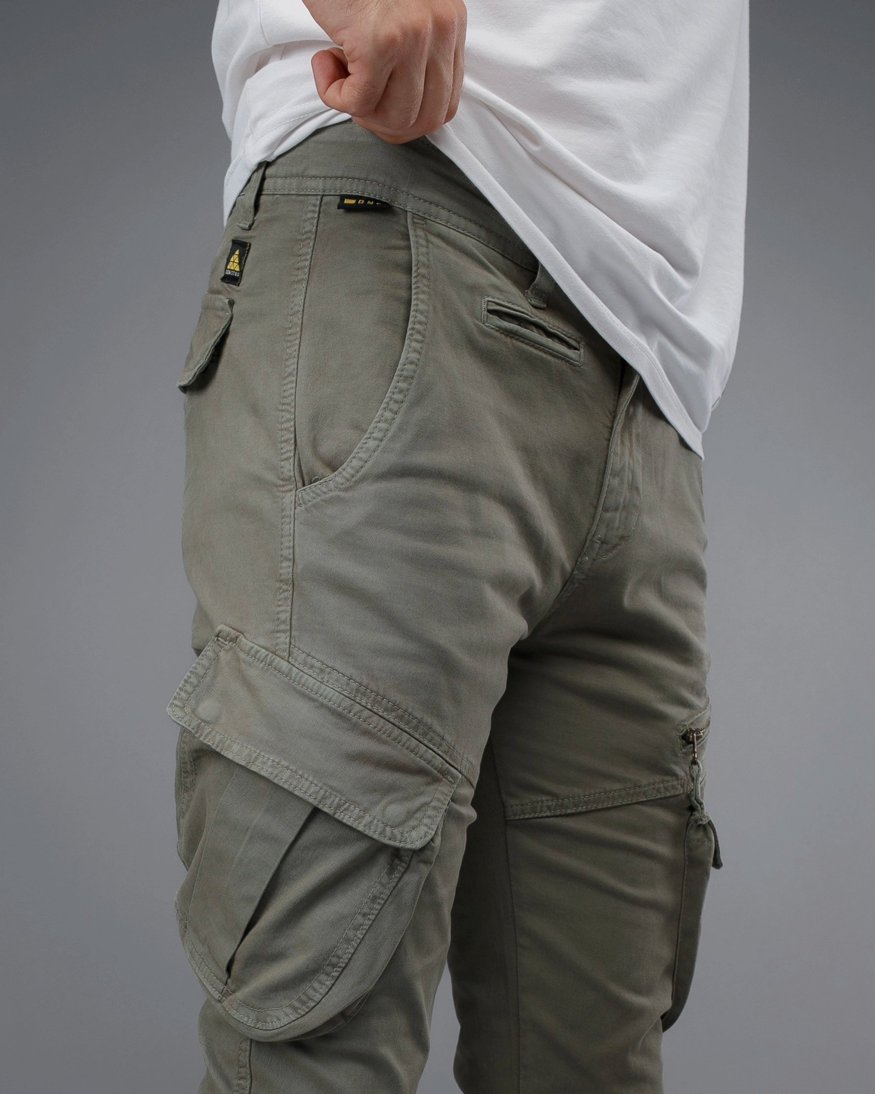 Person wearing beige cargo pants on a gray background