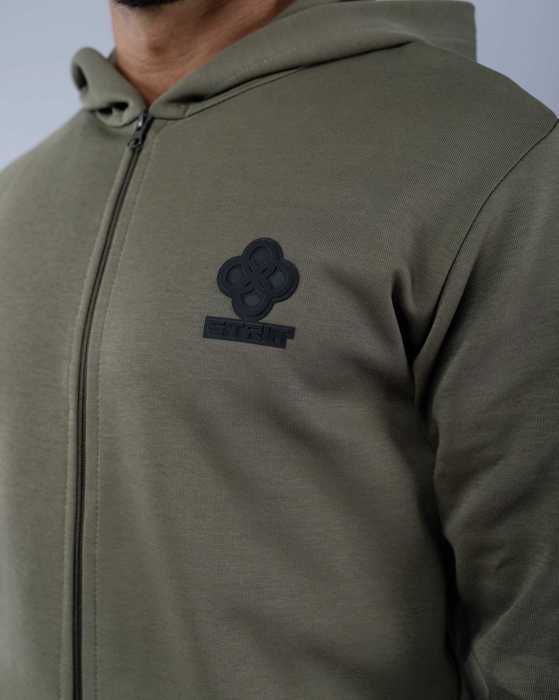 Close-up of a green hoodie with a logo on the chest against a gray background