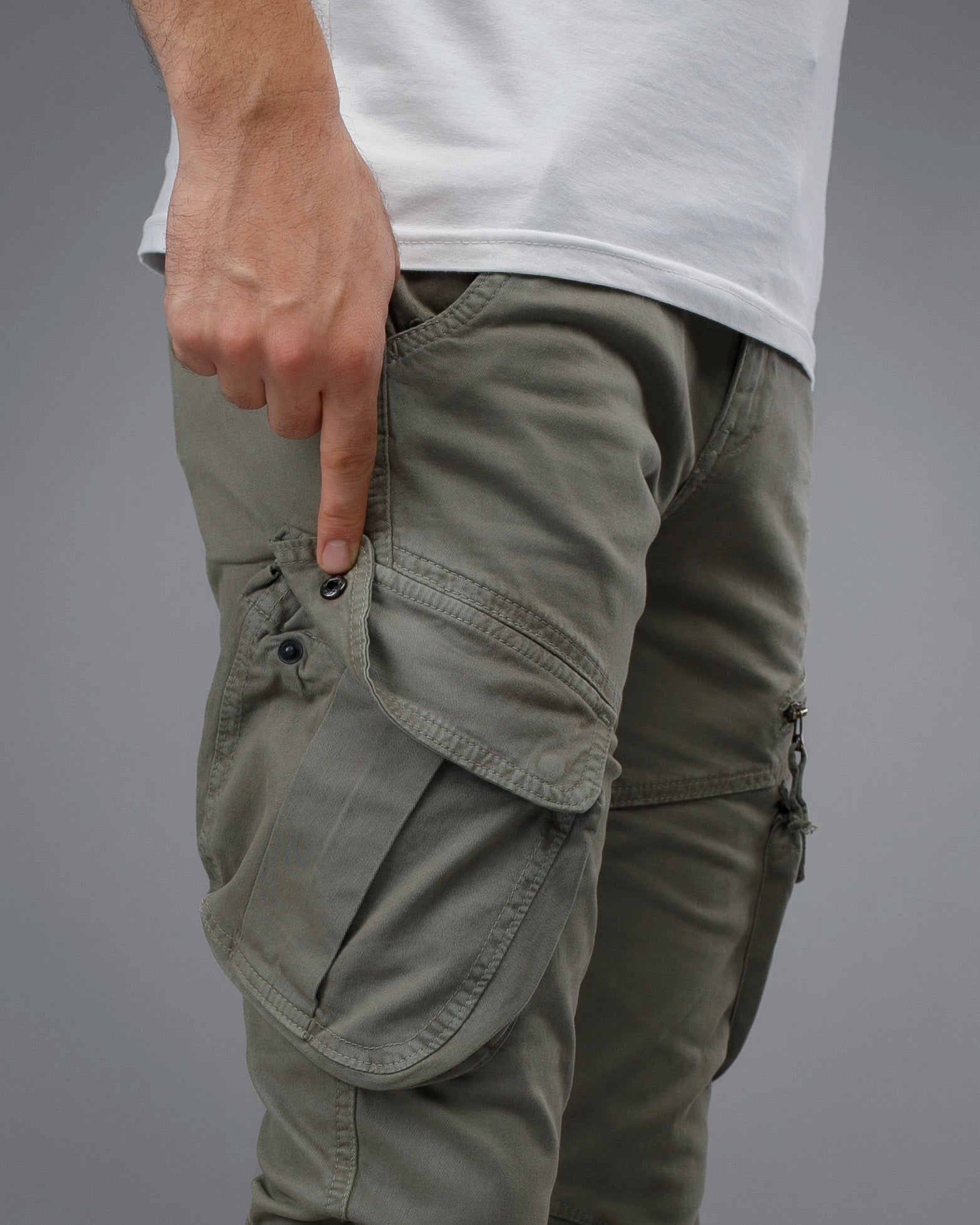 Person wearing olive green cargo pants on a gray background