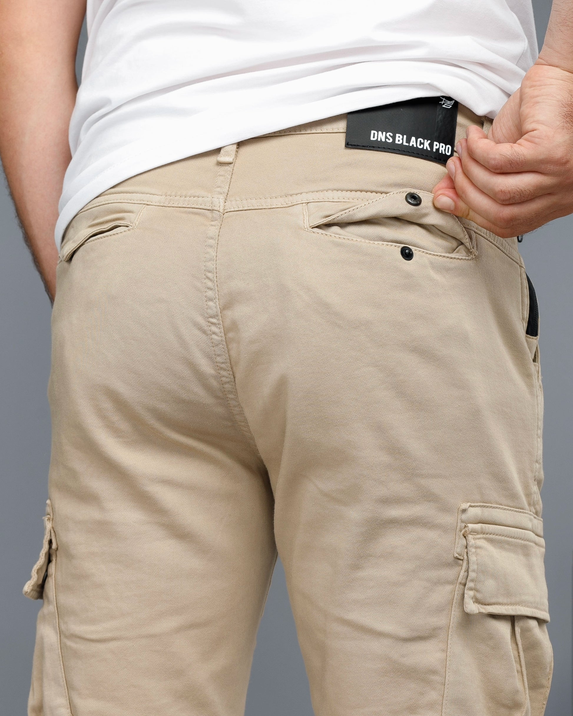 Beige cargo pants with a visible brand label on a gray background