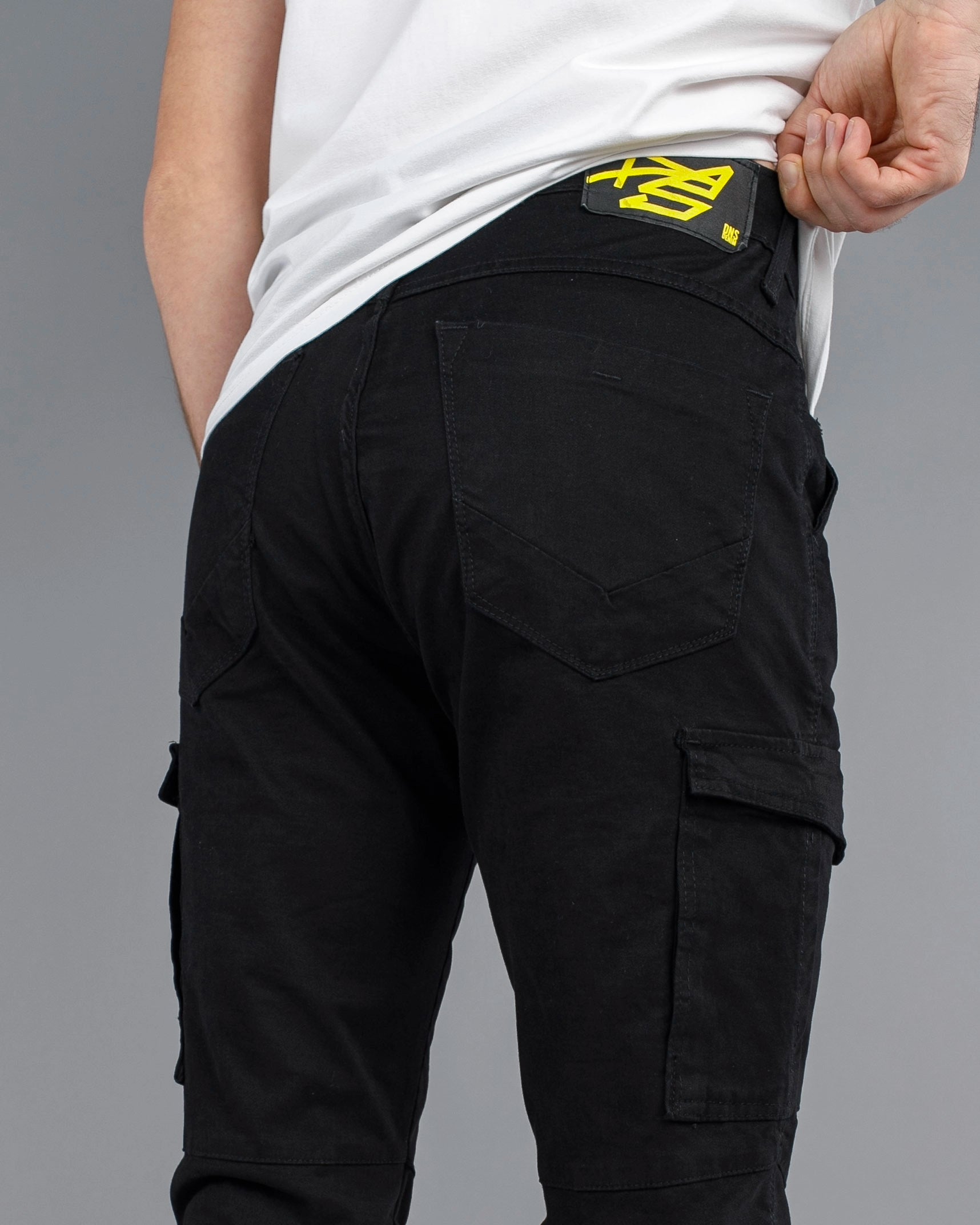 Black cargo pants with a brand logo on the back pocket against a gray background