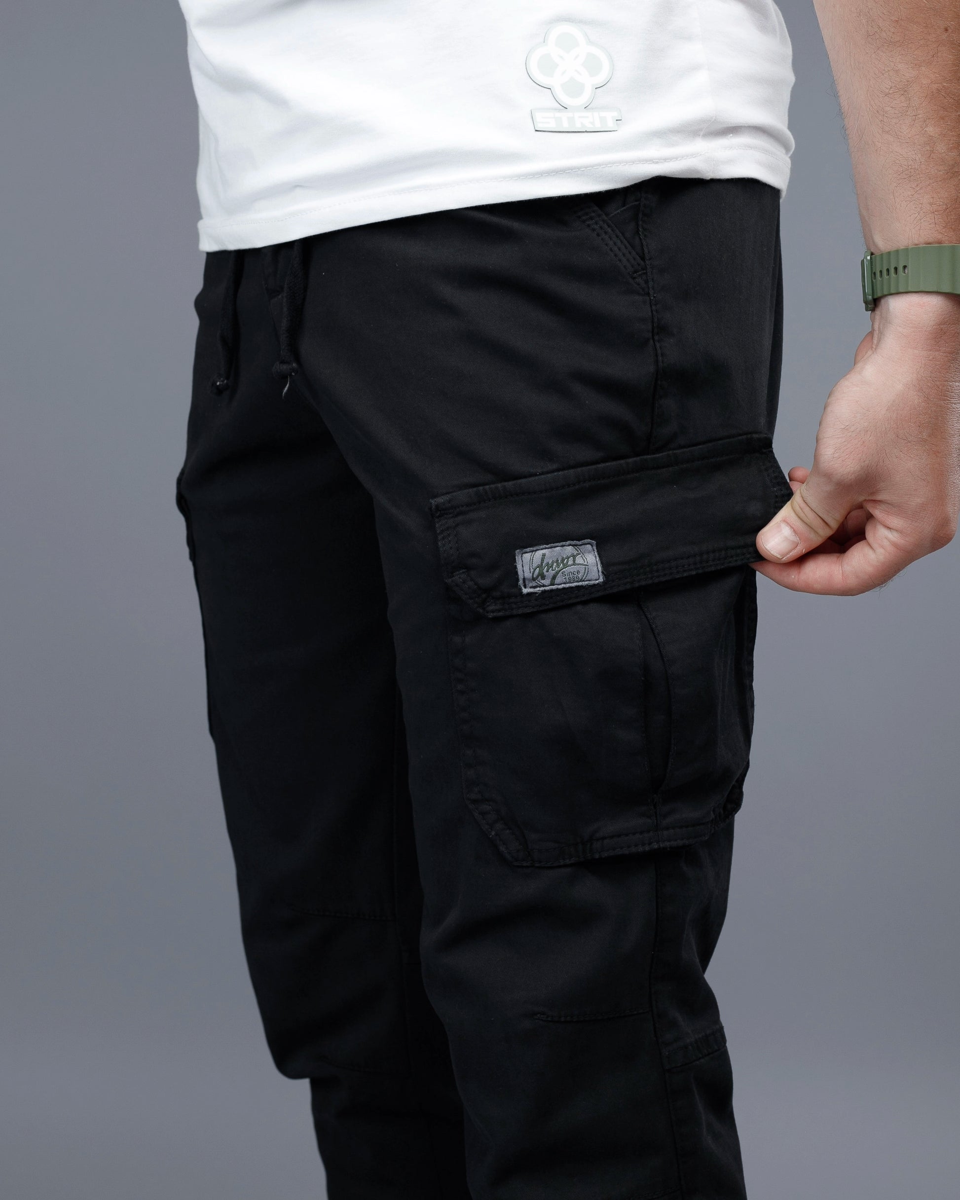 Person wearing black cargo pants with a gray background