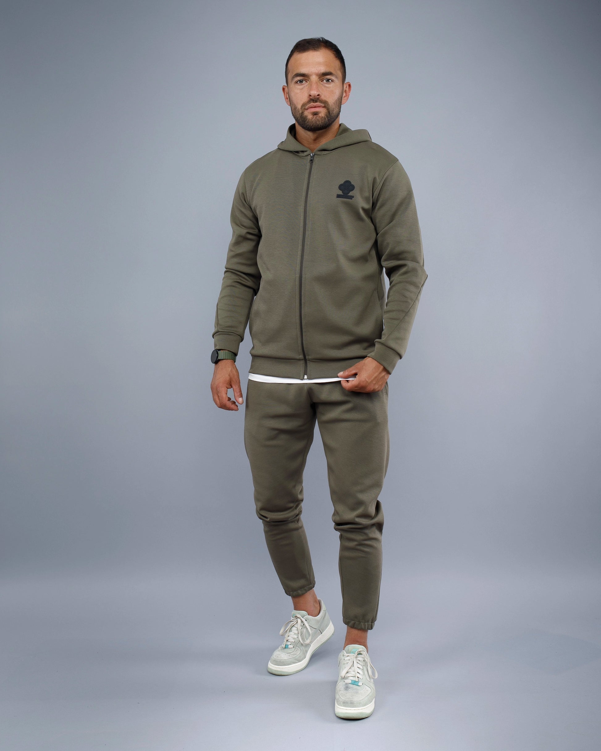 Man wearing a green tracksuit with a logo on a gray background