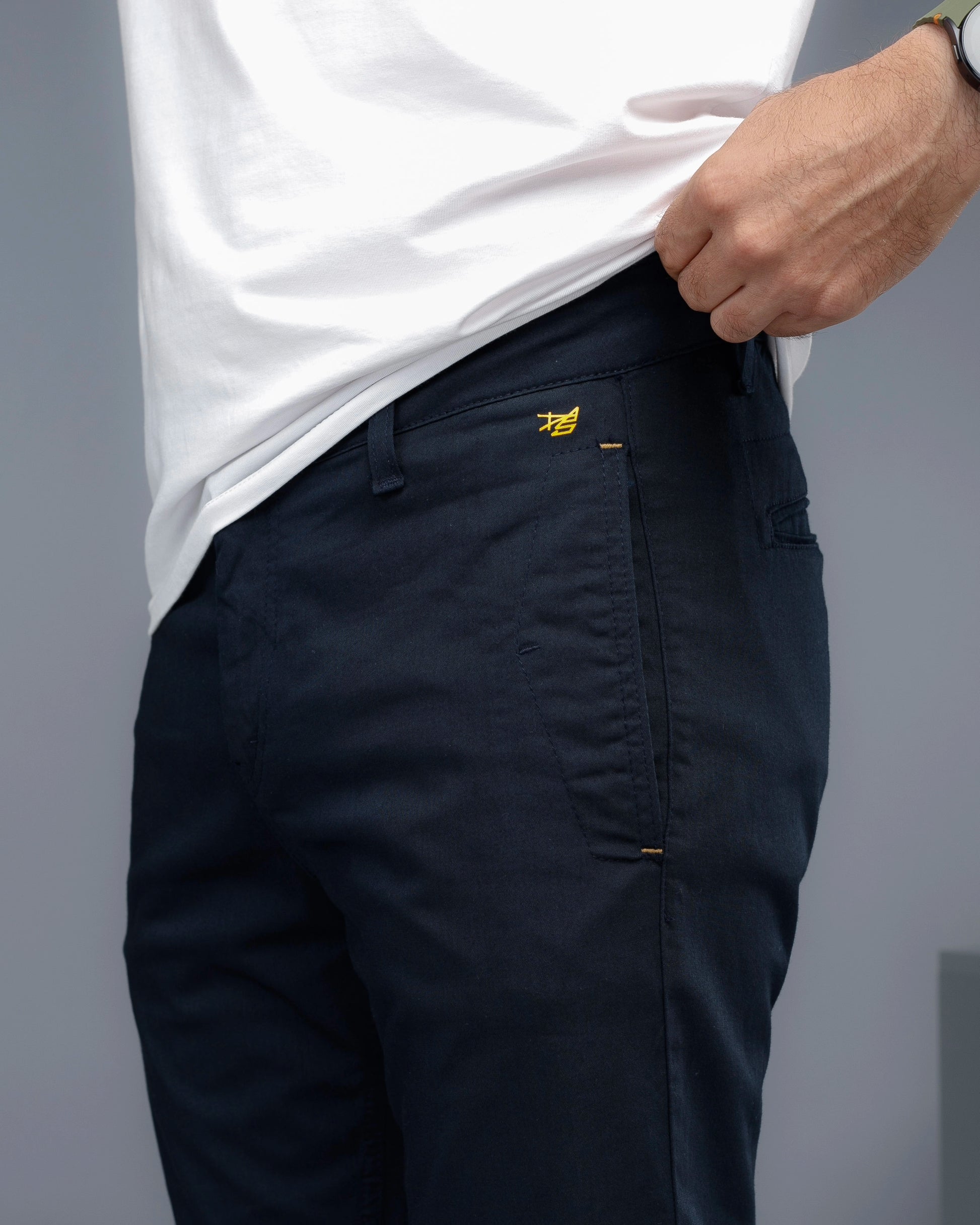 Person wearing navy pants with a brand logo on a gray background