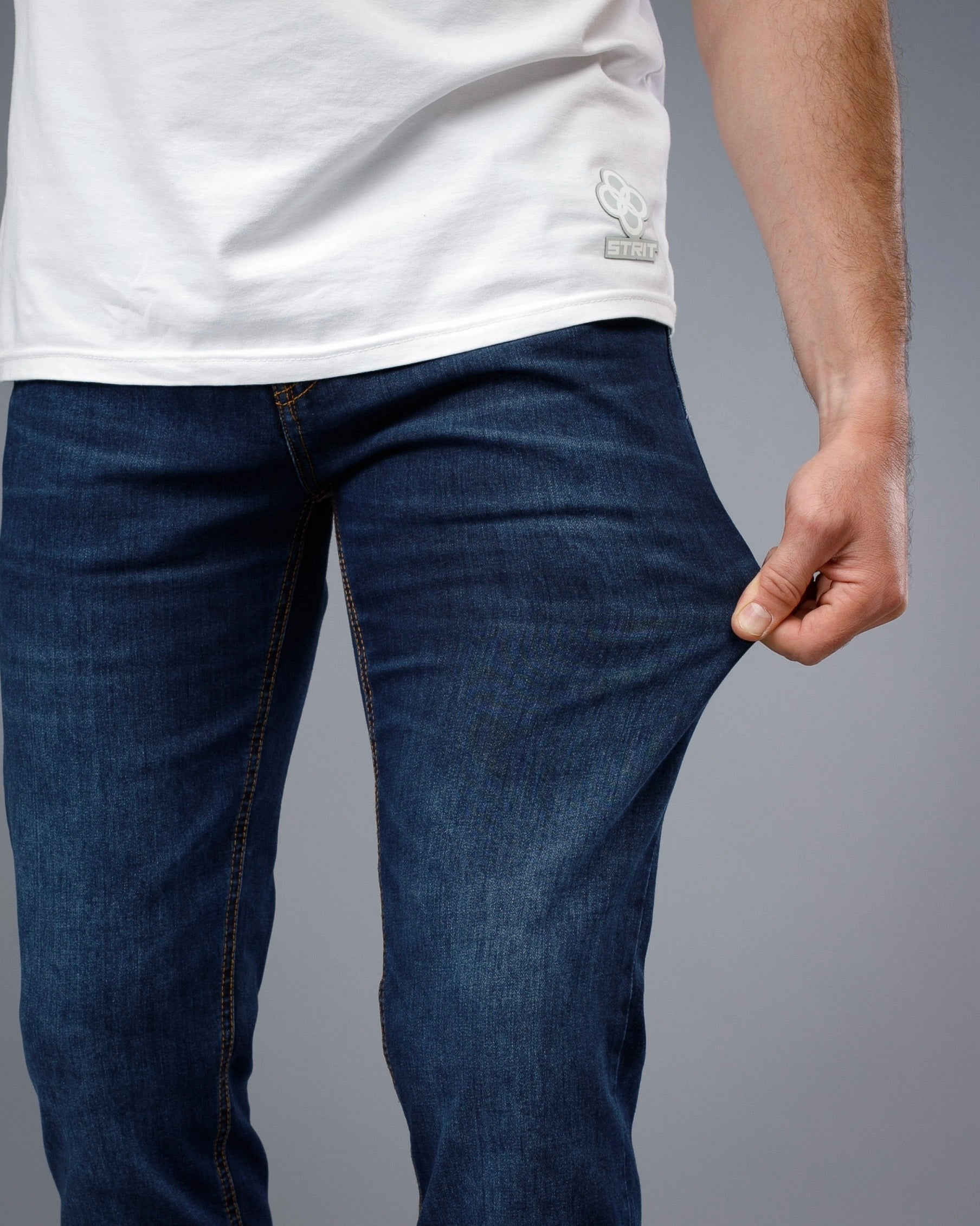 Person wearing blue jeans and a white t-shirt on a gray background