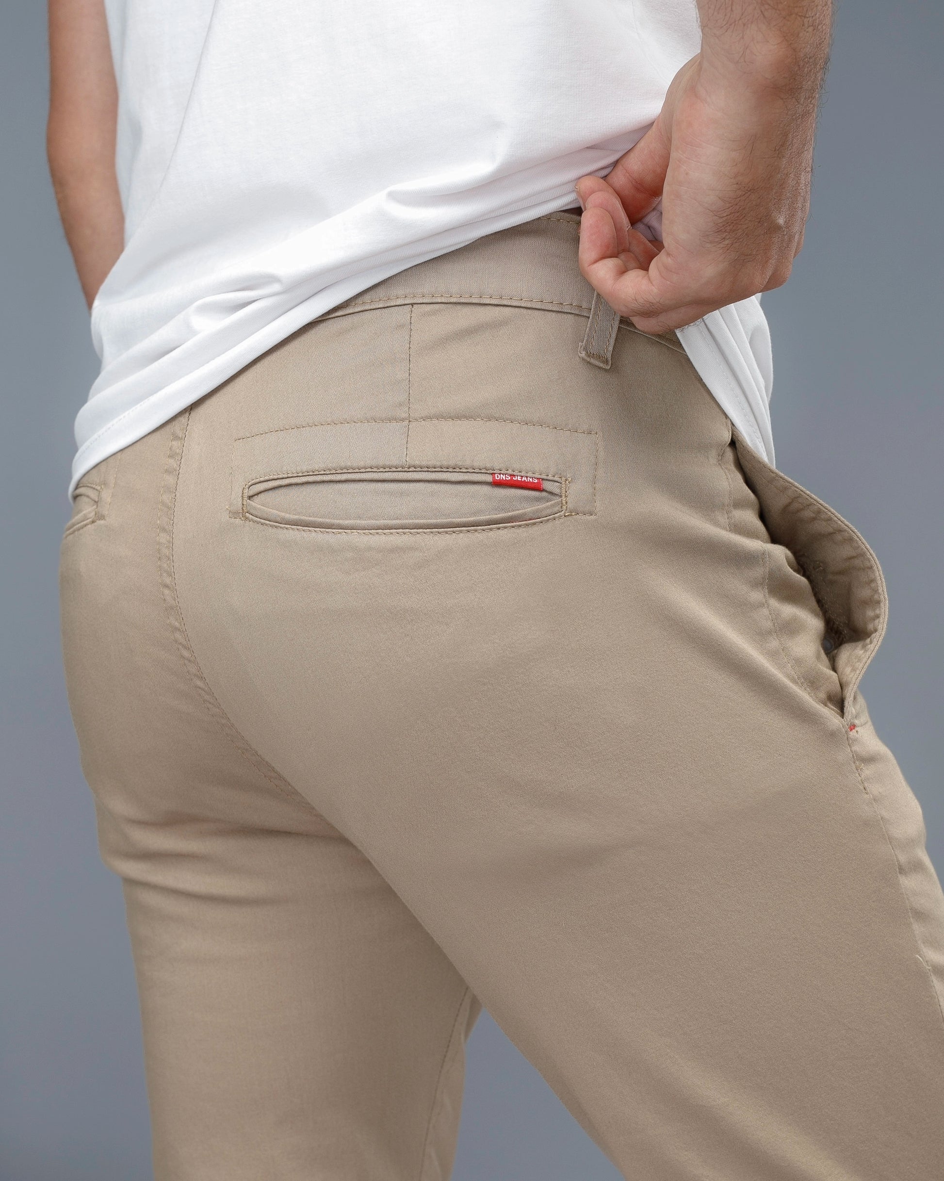 Beige pants with a red tag on a gray background