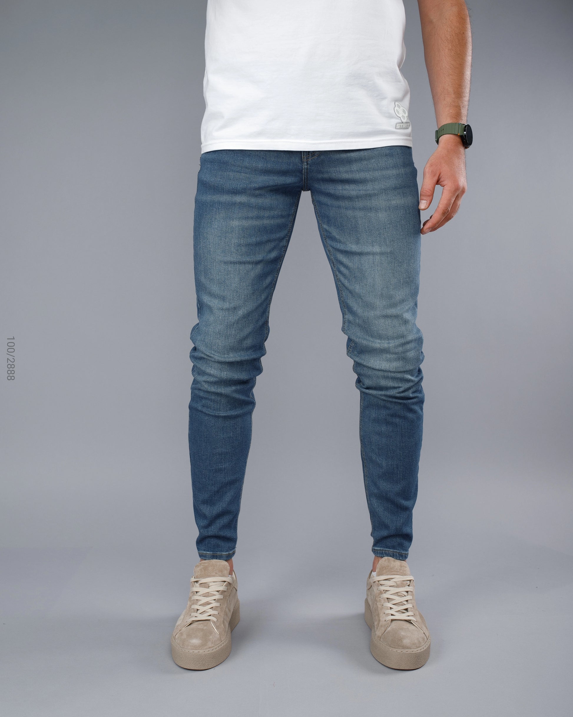 Person wearing blue jeans and a white shirt on a gray background