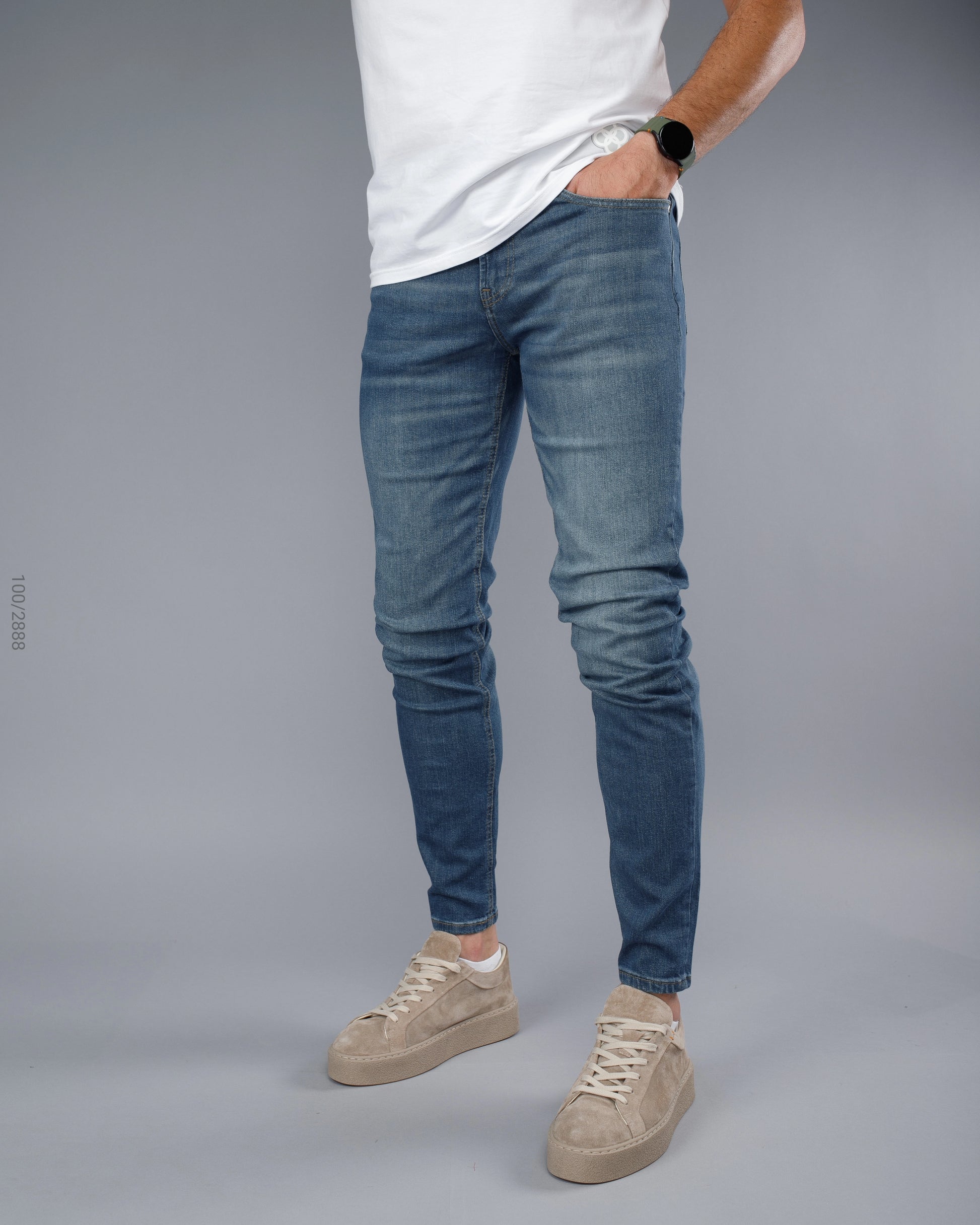 Person wearing blue jeans and a white shirt on a gray background