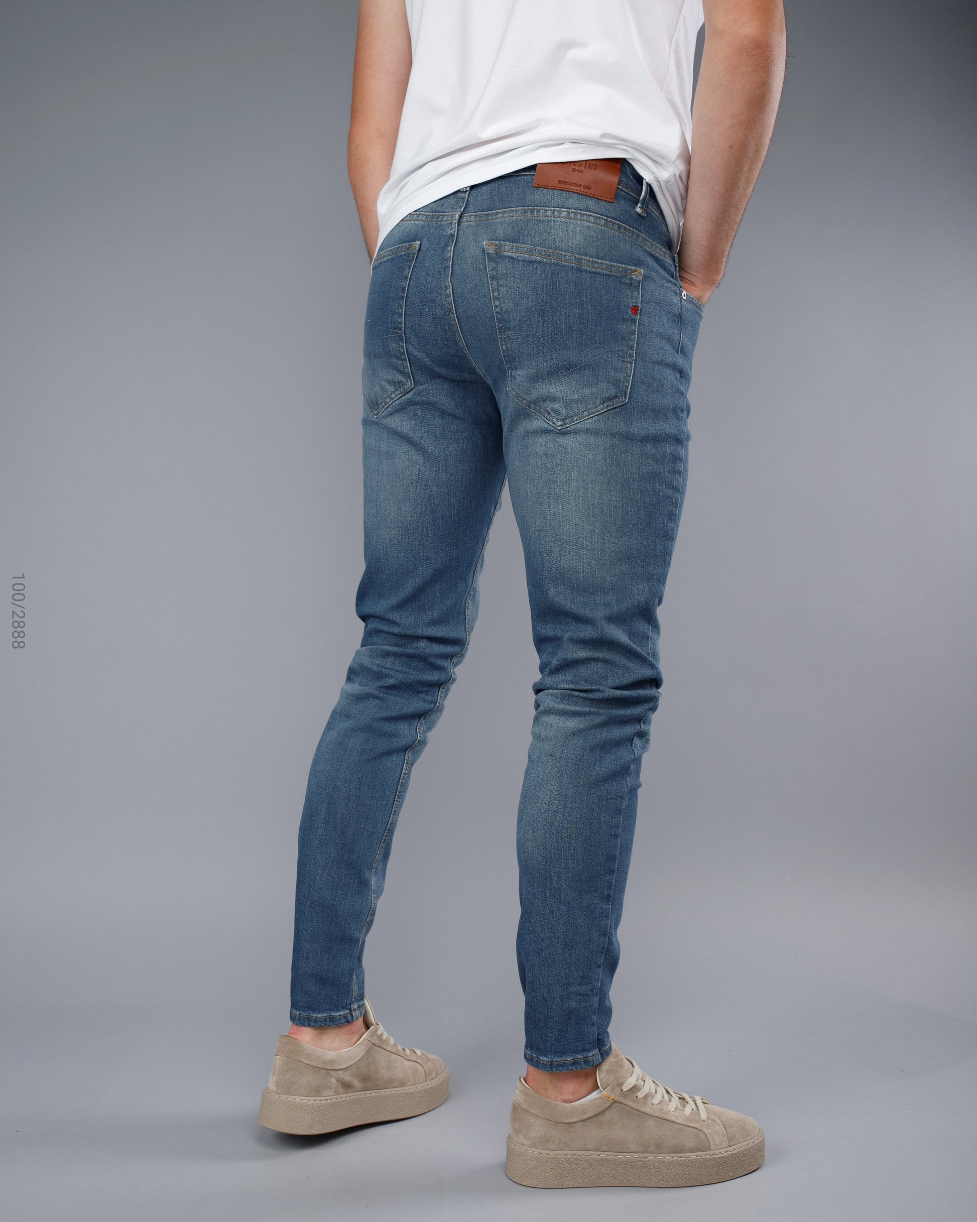 Person wearing blue jeans and a white shirt on a gray background