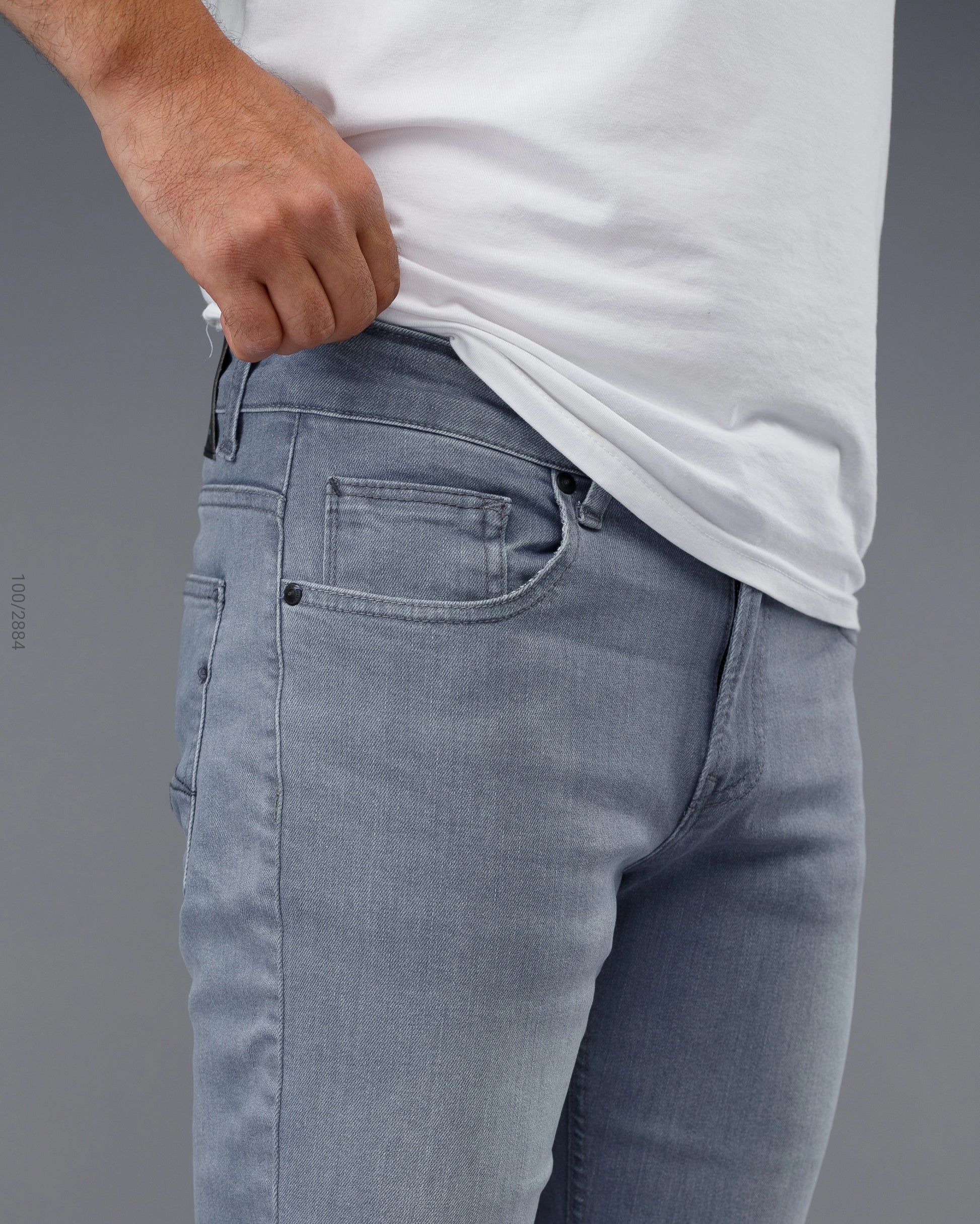 Person wearing light blue jeans and a white t-shirt on a gray background