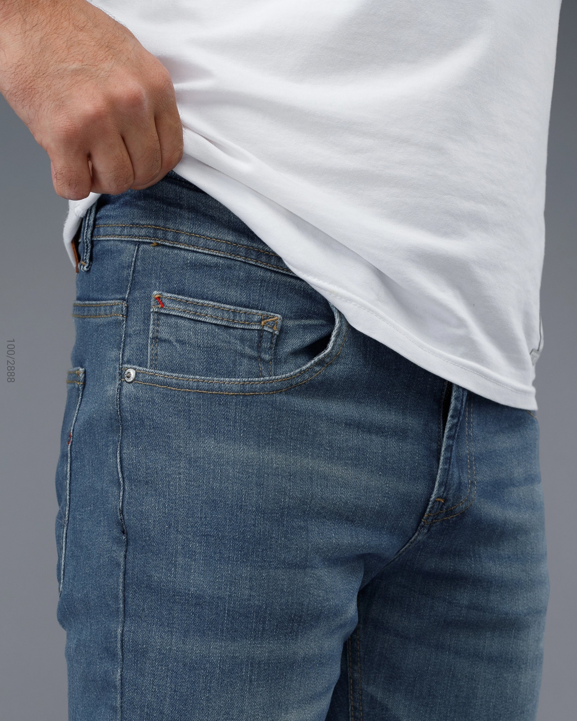 Person wearing blue jeans and a white shirt on a gray background